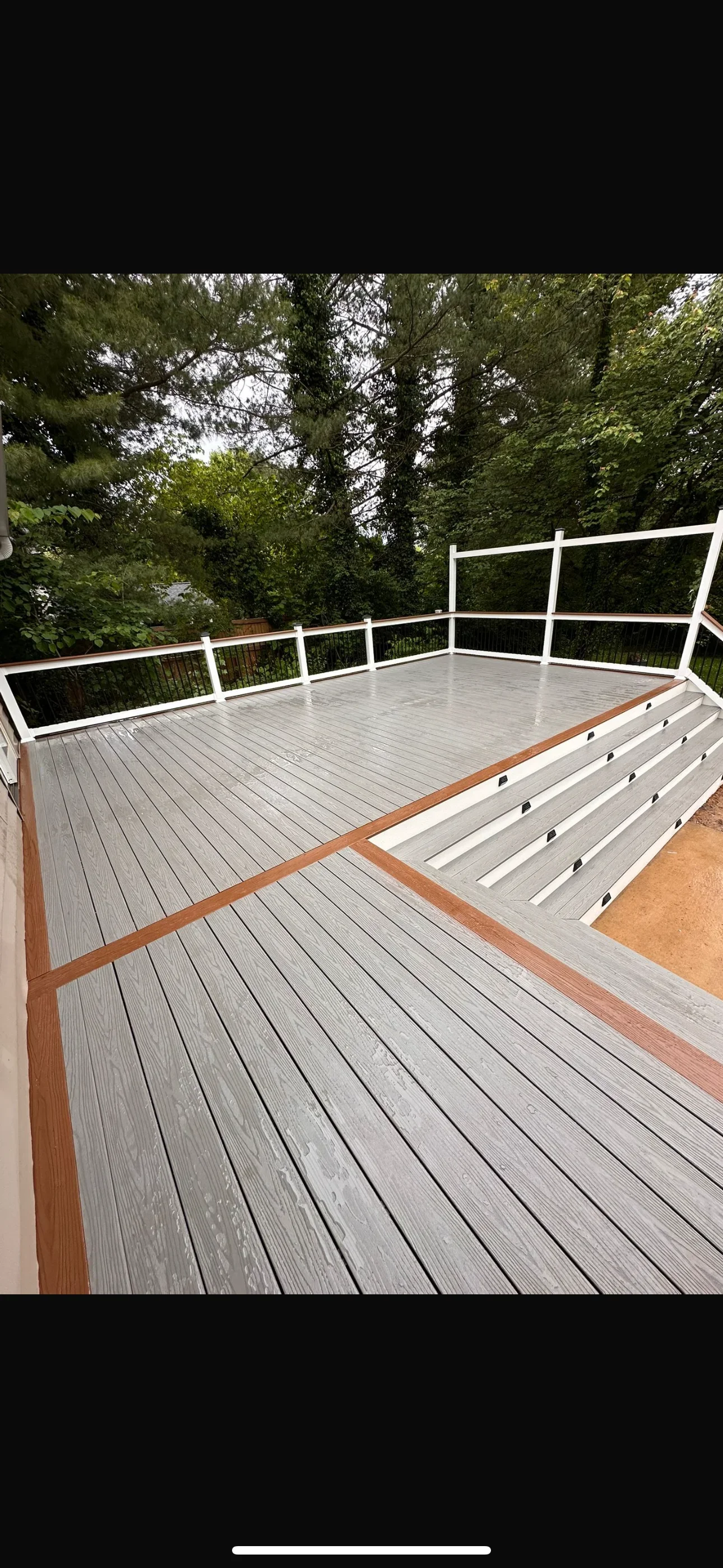 Gray composite deck with white railing overlooking wooded yard