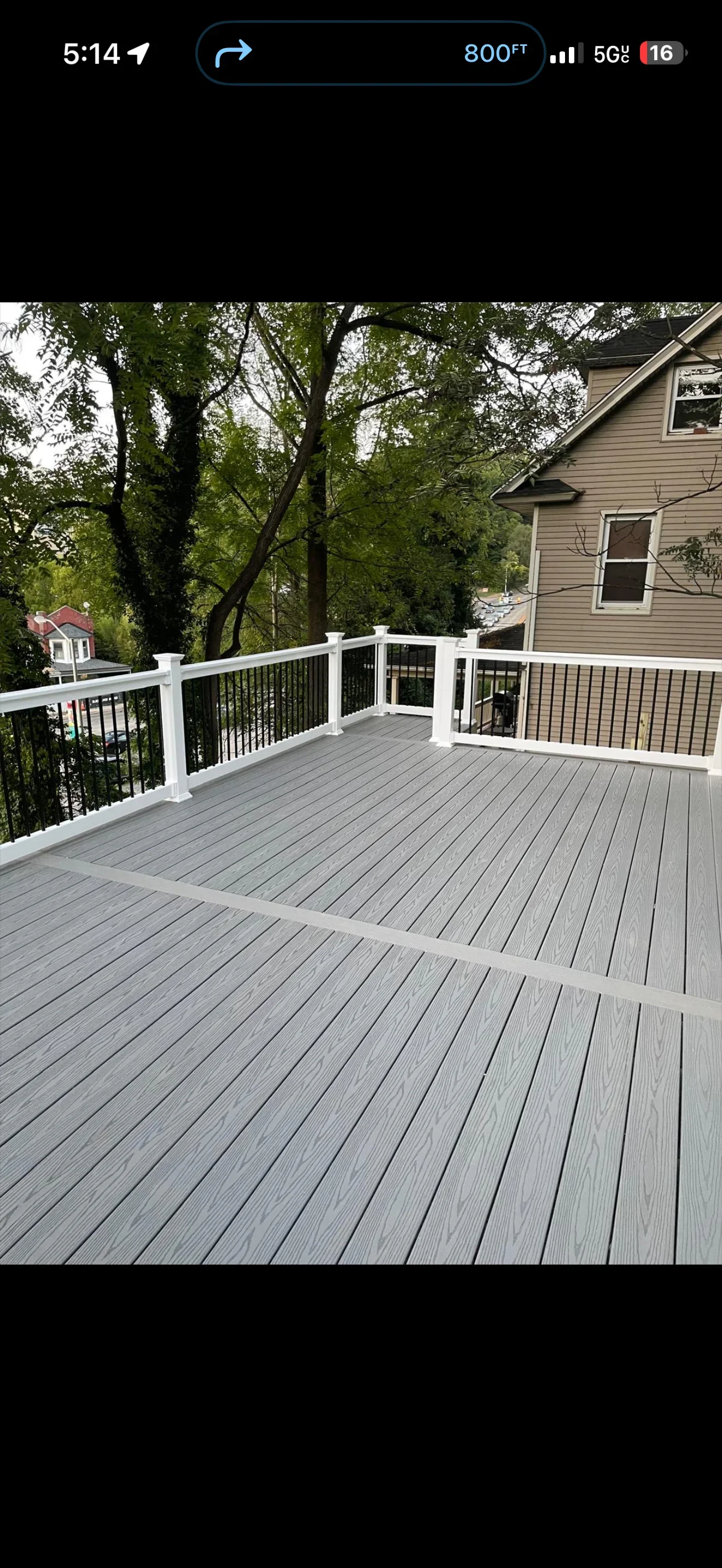 Gray composite deck with white railings and black metal balusters overlooking wooded yard