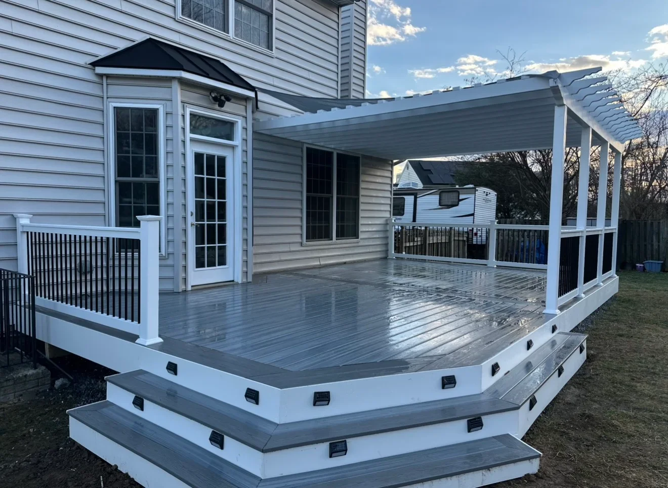 Two-level composite deck with covered patio, white railings, and LED lighting