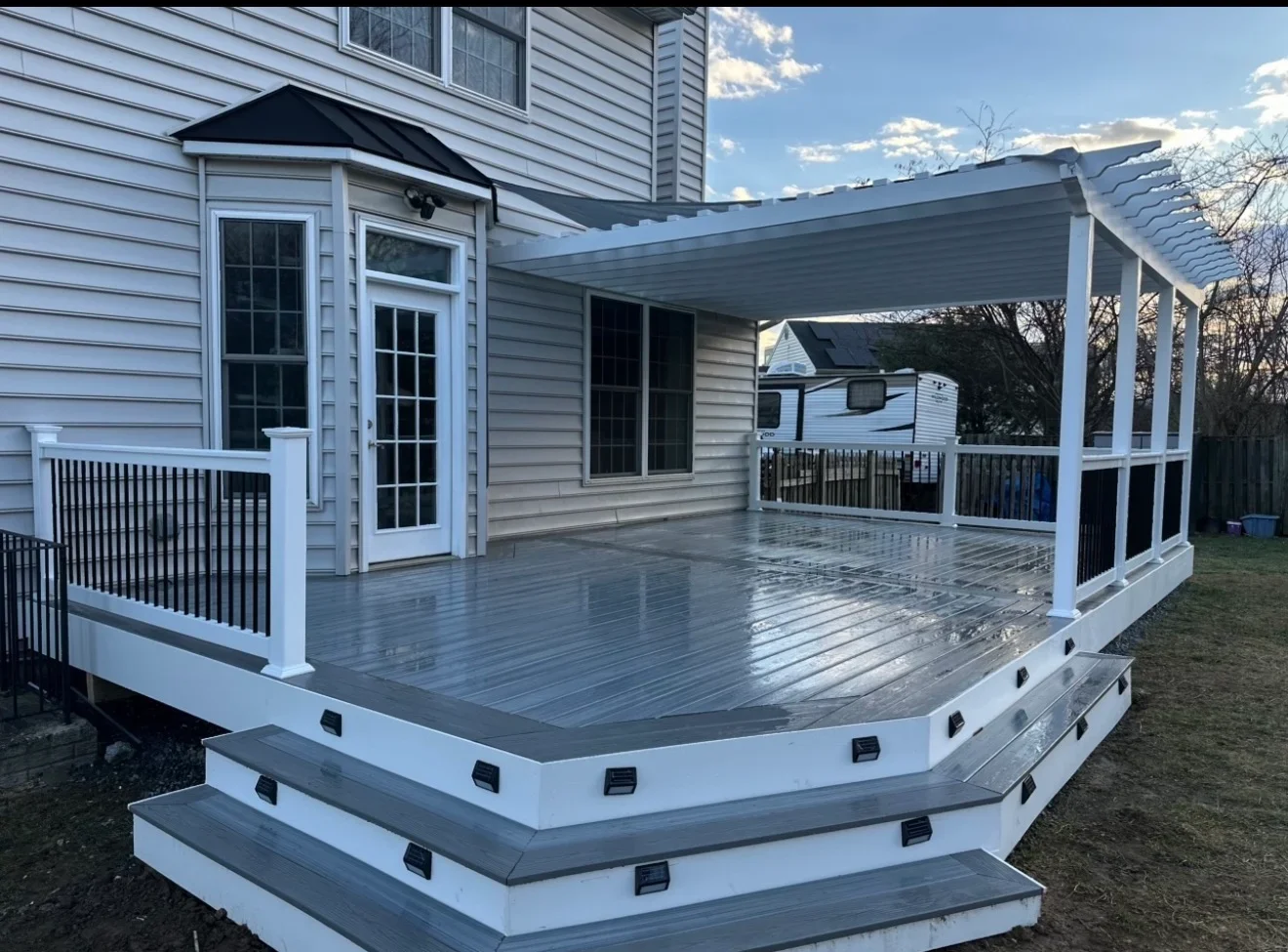 Two-level composite deck with white railings, covered patio, and gray decking