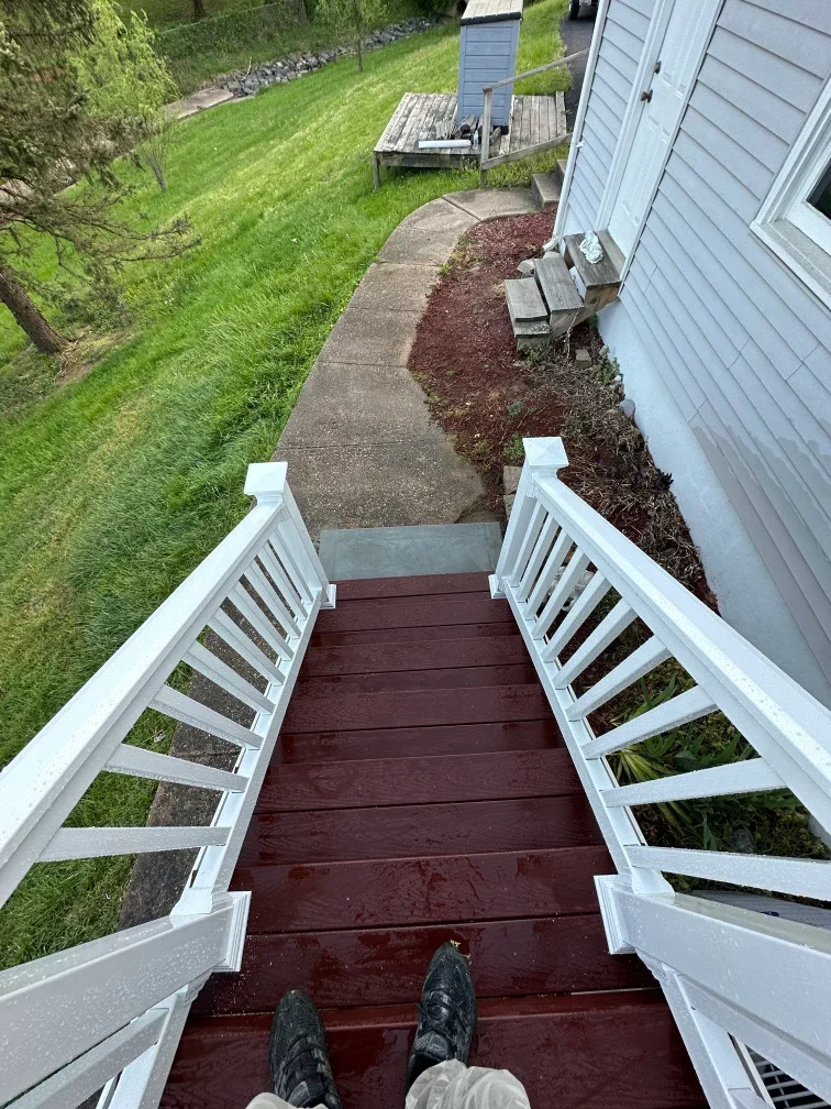 Burgundy composite deck with white railings overlooking landscaped backyard