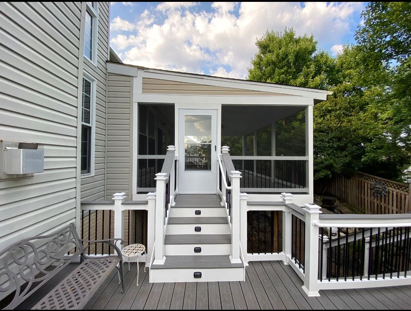 Multi-level gray composite deck with white railings, screened porch, and stairs