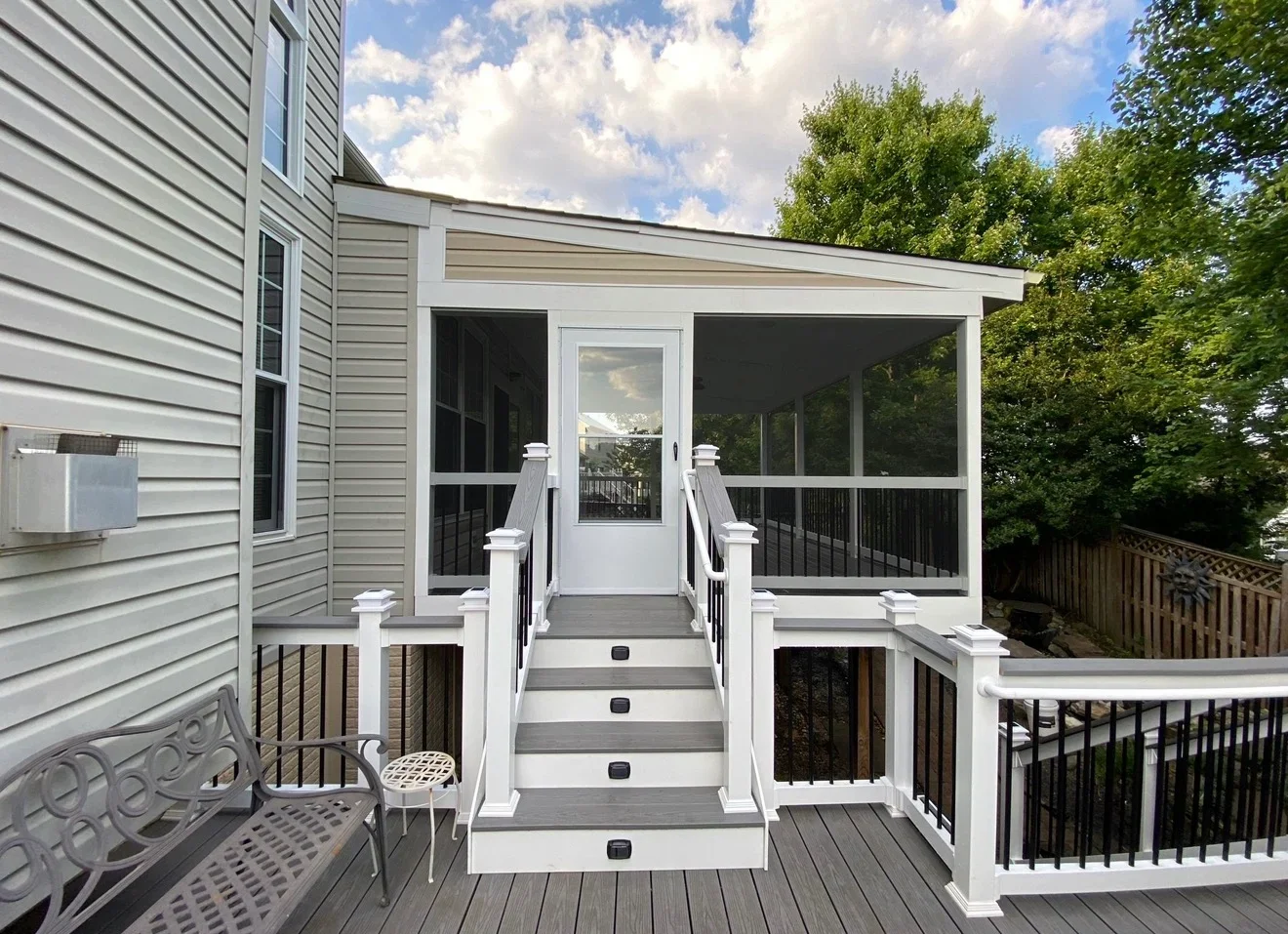 Two-level composite deck with screened porch, white railings, and black metal balusters