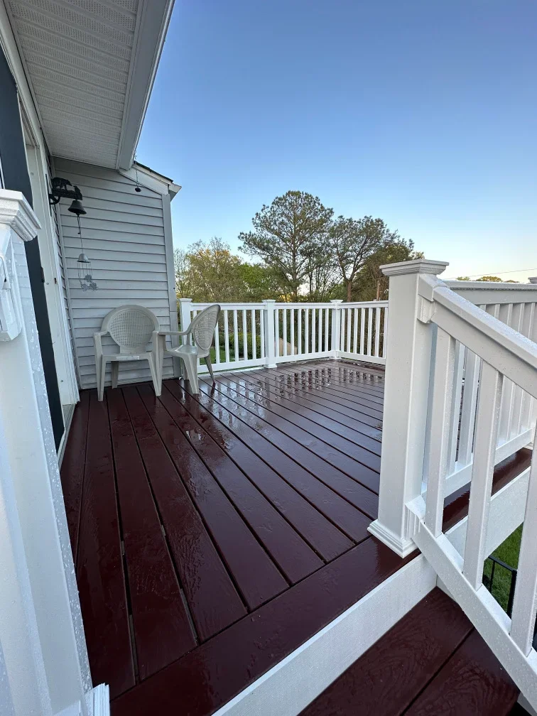 Elevated composite deck with white vinyl railings and post caps overlooking trees