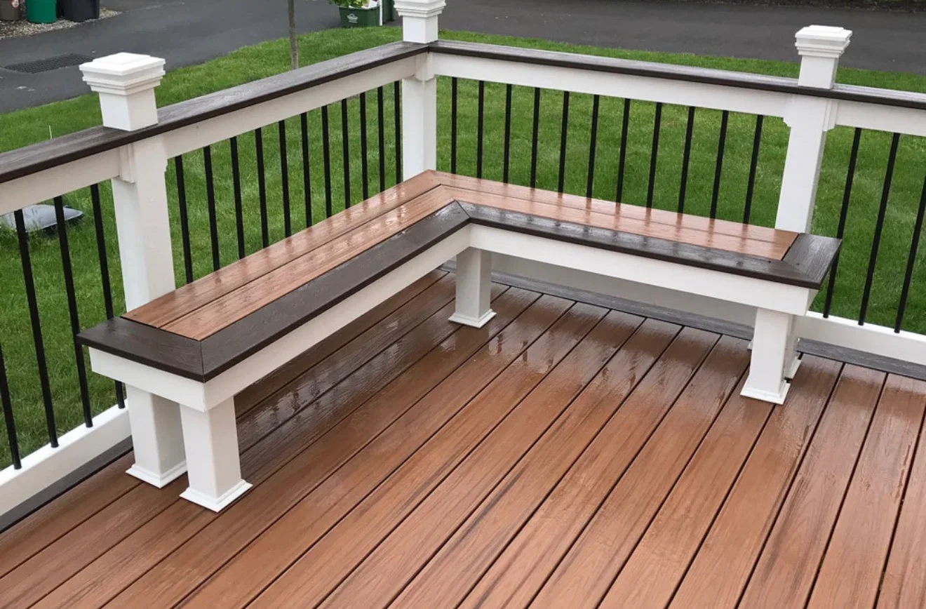 Composite deck with built-in bench seating, black railings, and white posts overlooking lawn