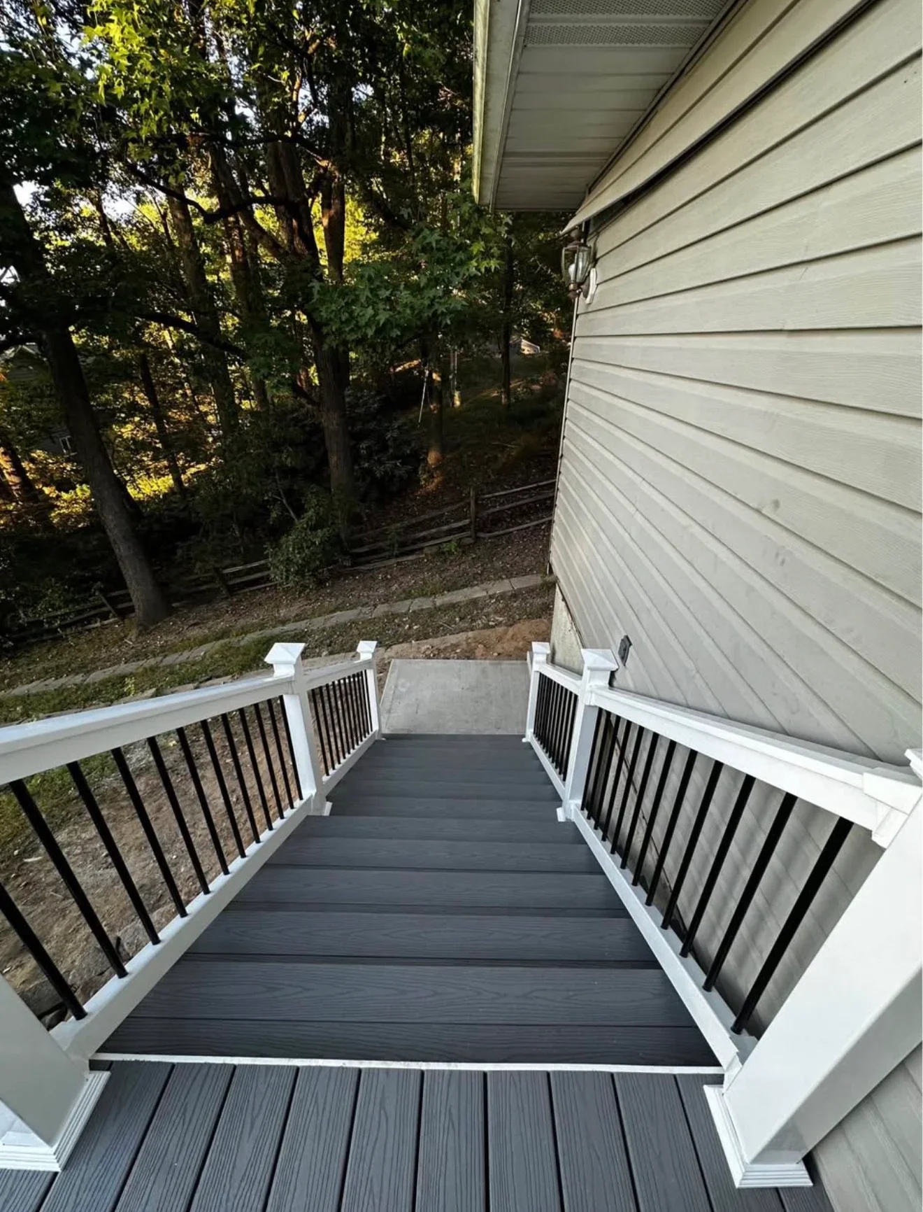 Dark composite deck with white railings and black metal spindles adjacent to house siding