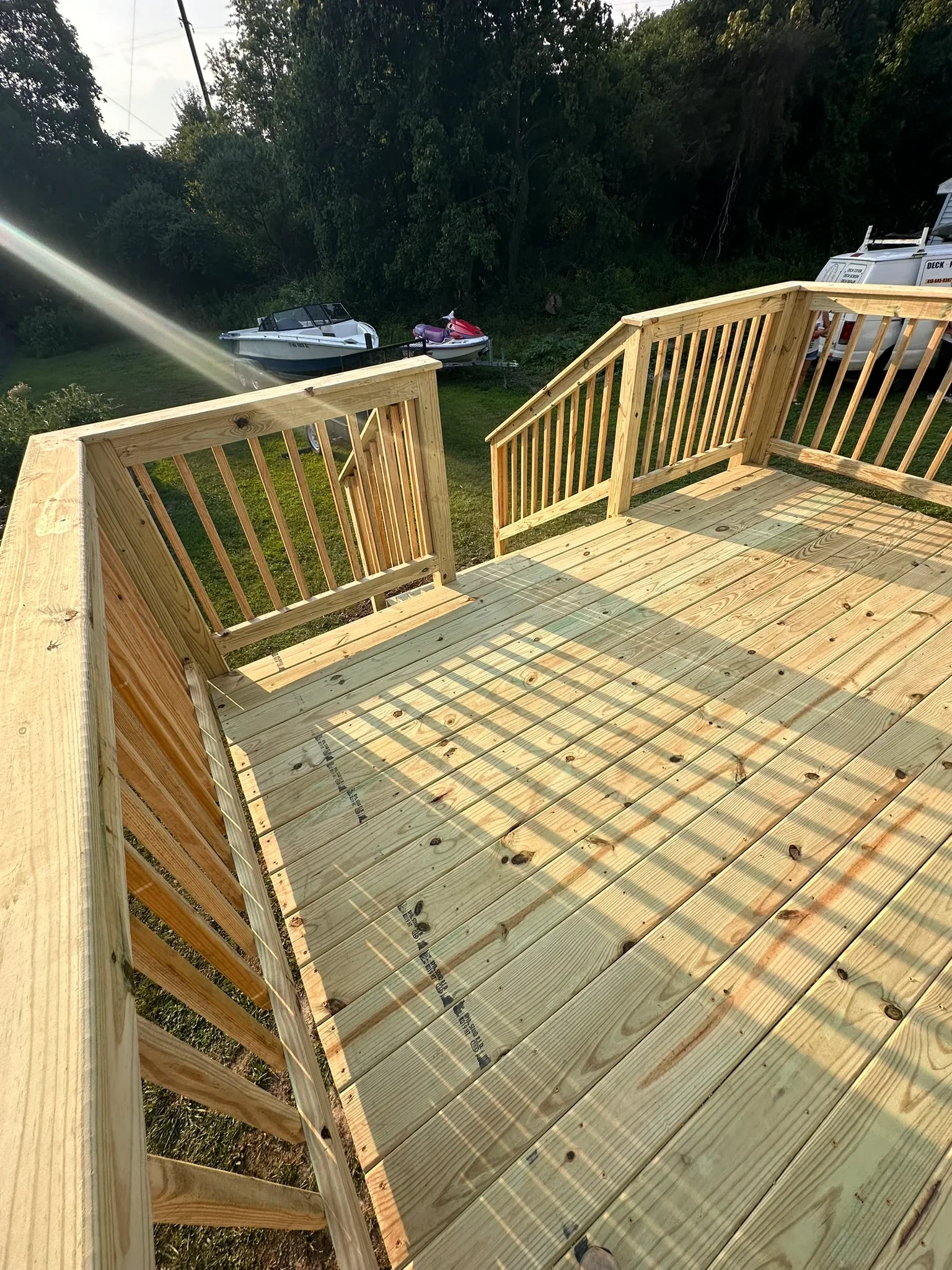 New wooden deck with railings overlooking waterfront with boats docked below
