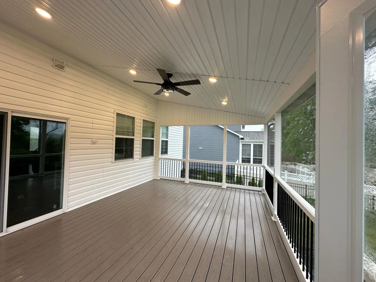 Covered composite deck with white ceiling, recessed lights, and black metal railings