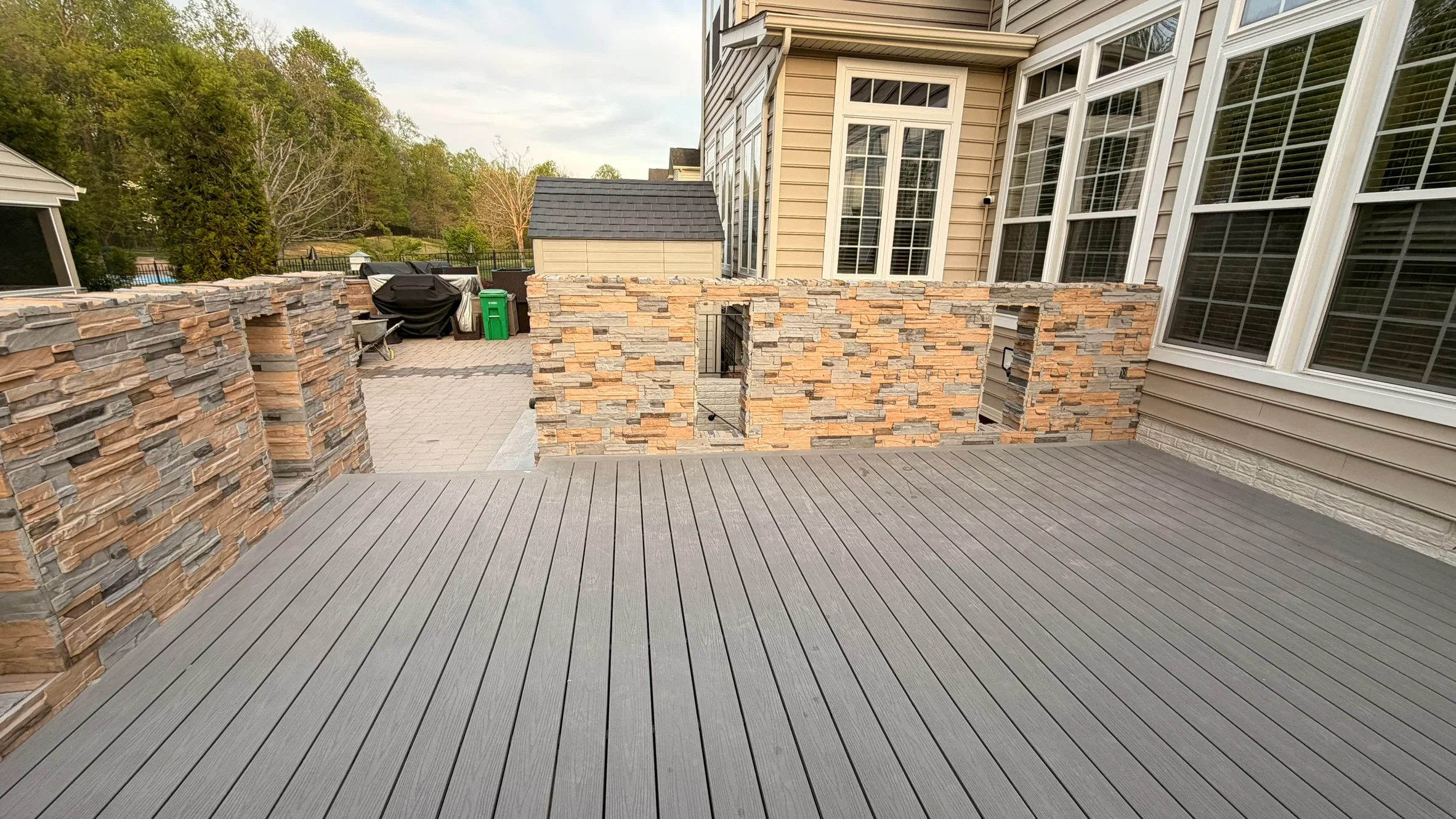 Gray composite deck with stacked stone pillars and raised patio section