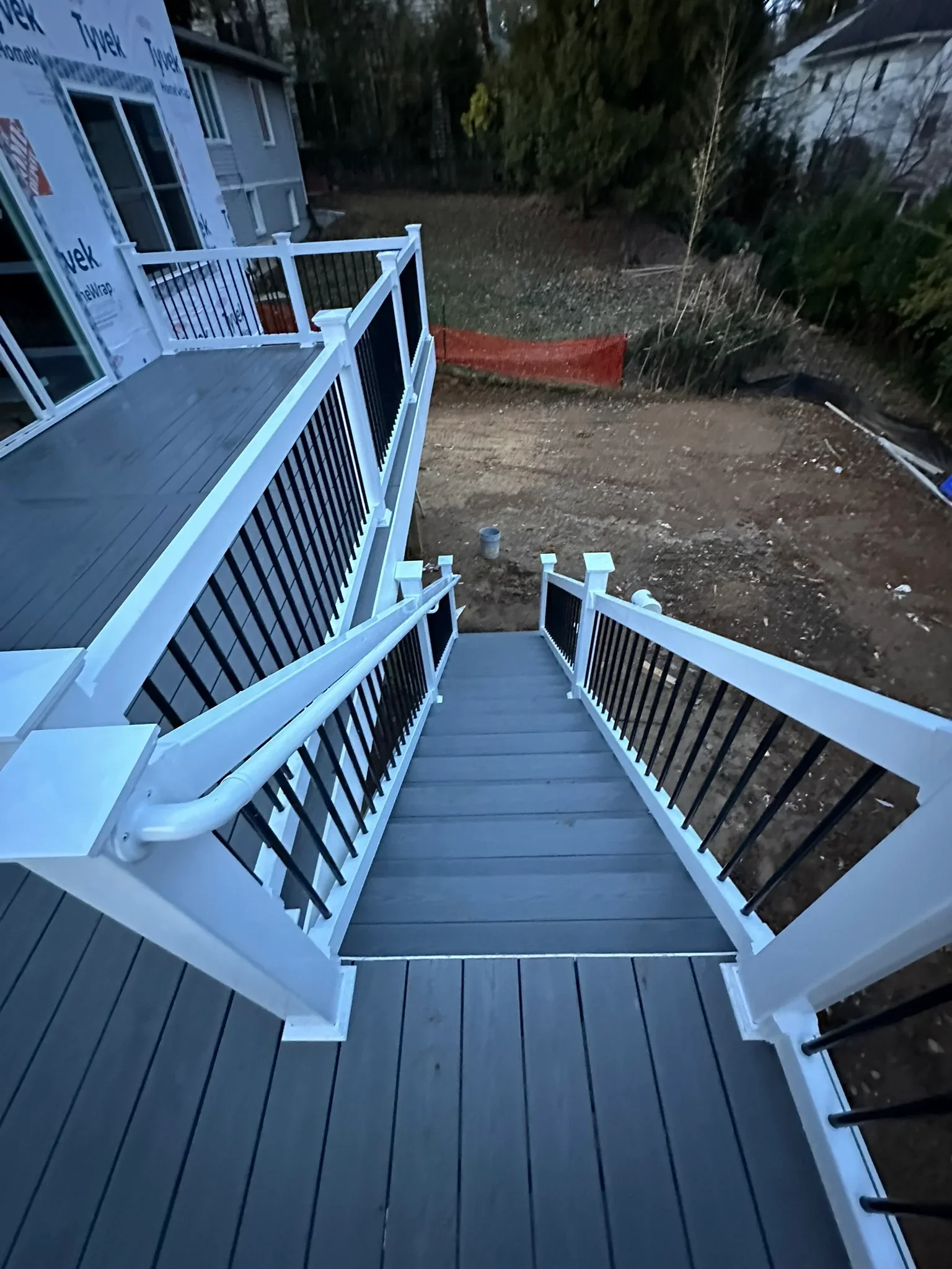 Multi-level gray composite deck with white vinyl railings and black balusters overlooking backyard